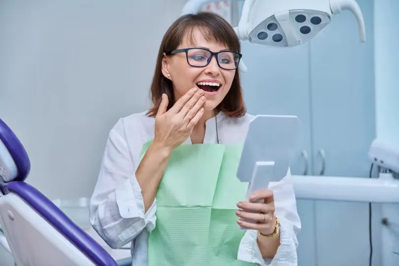 Patient admiring her smile in a hand mirror