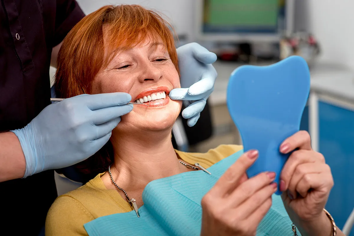 Patient checking her smile in a mirror during a dental visit