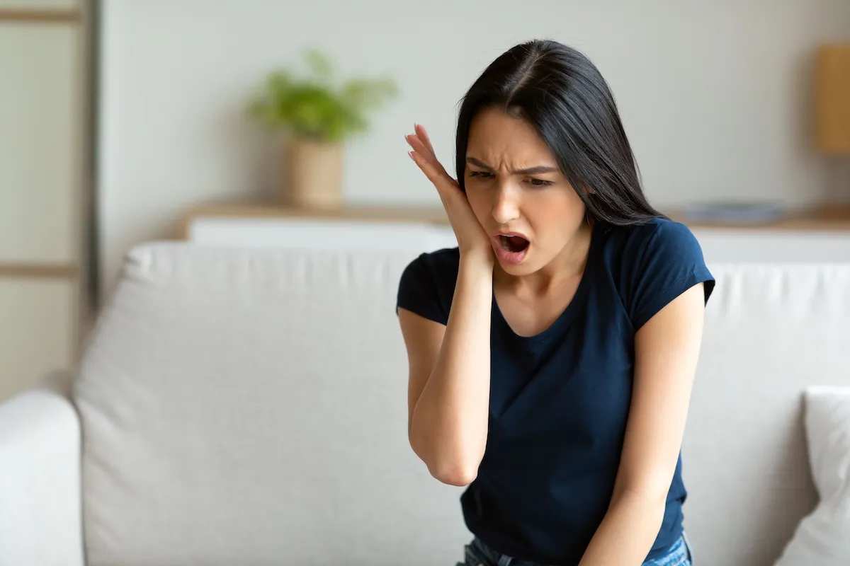 Woman holding her jaw with tooth pain